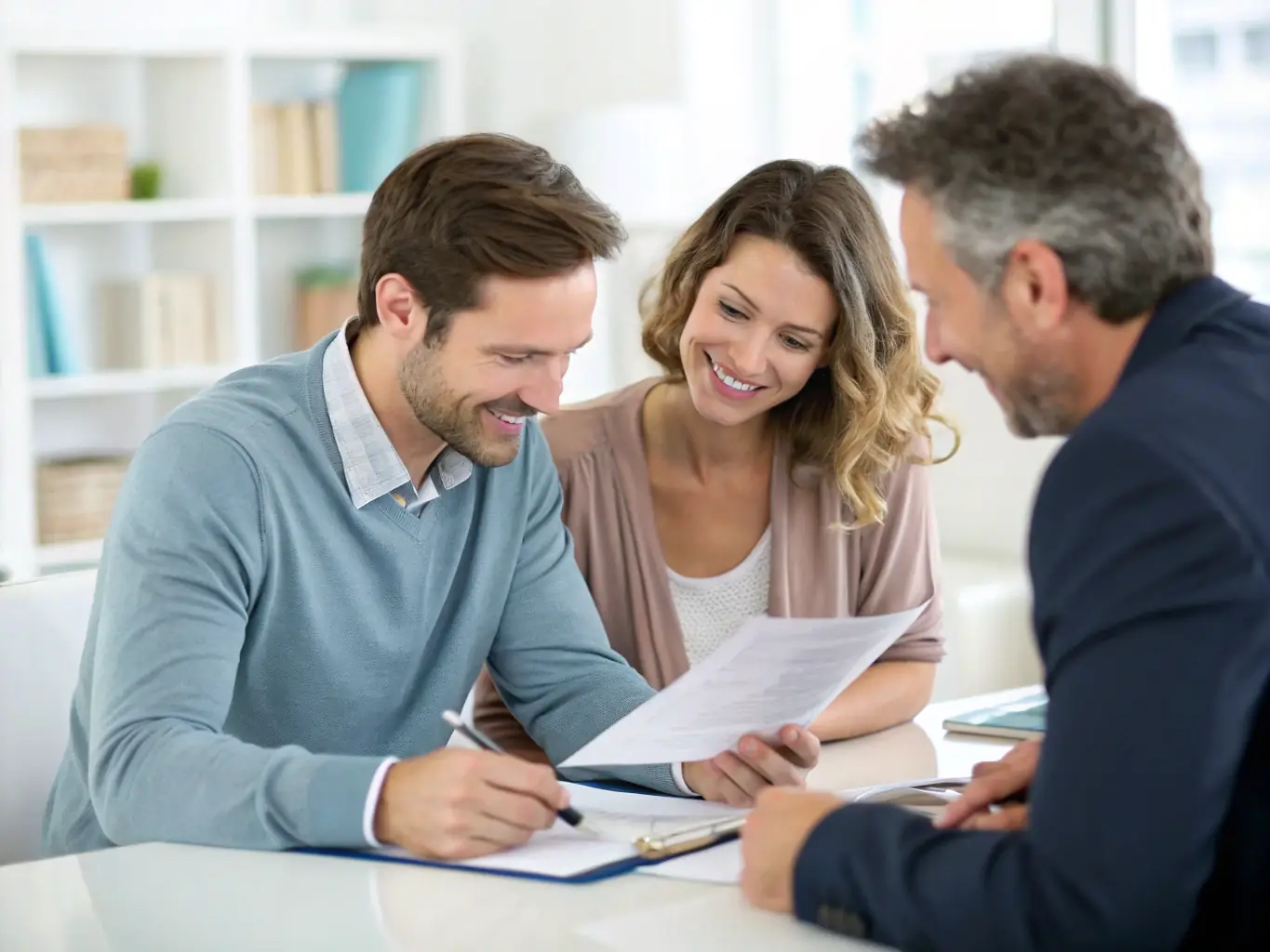 An image of a happy couple reviewing mortgage documents with a financial advisor in a modern, sunlit office setting. The atmosphere is professional yet friendly, emphasizing trust and collaboration.